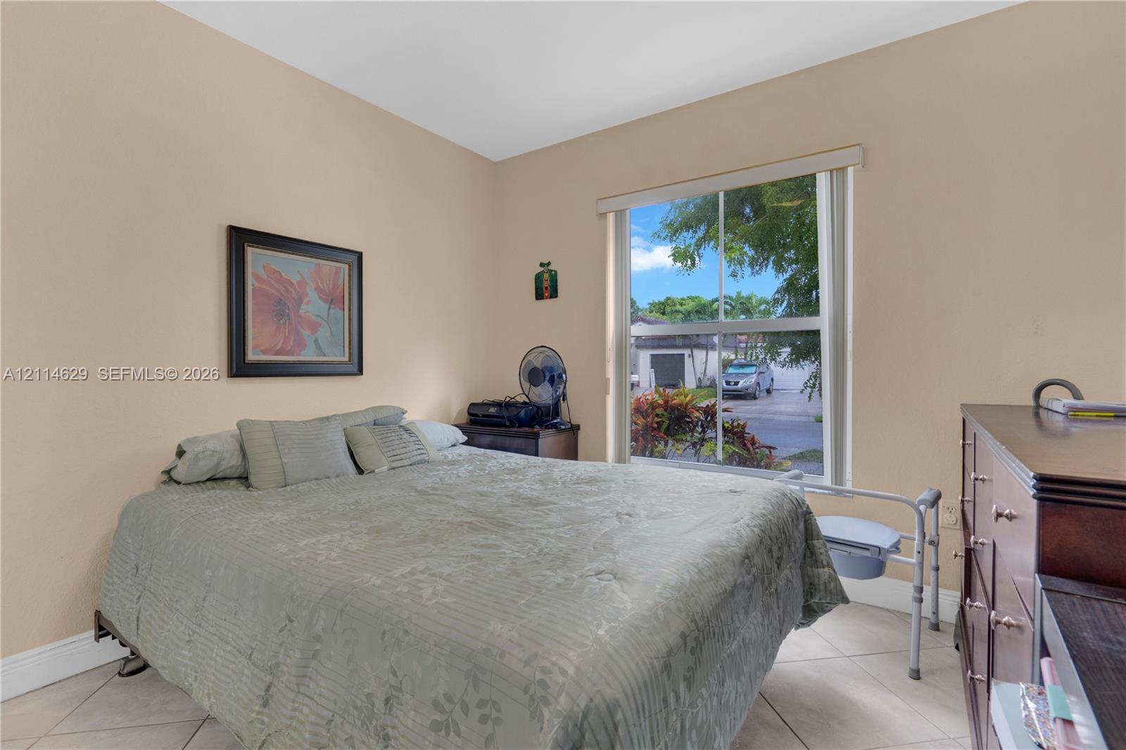 Interior room featuring neutral-toned walls, tile flooring, and a large single-hung window with a roller shade