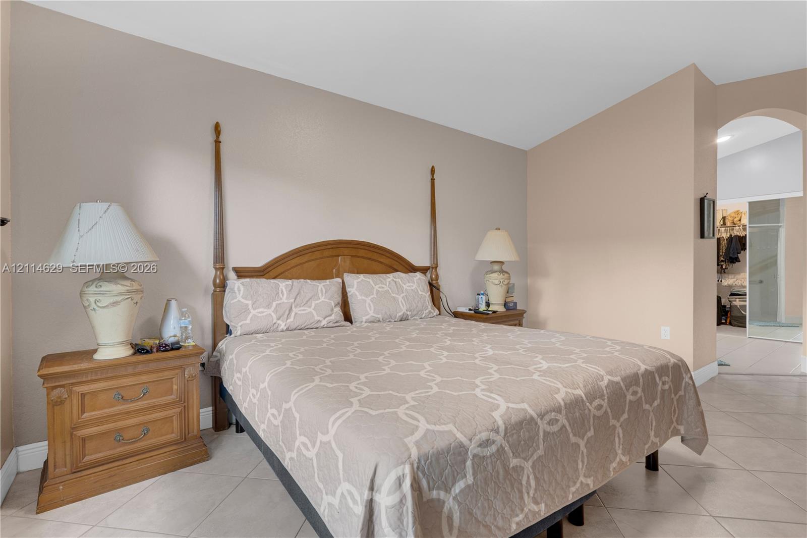 Neutral-toned walls, vaulted ceilings, and large-format tile flooring featuring an arched entryway