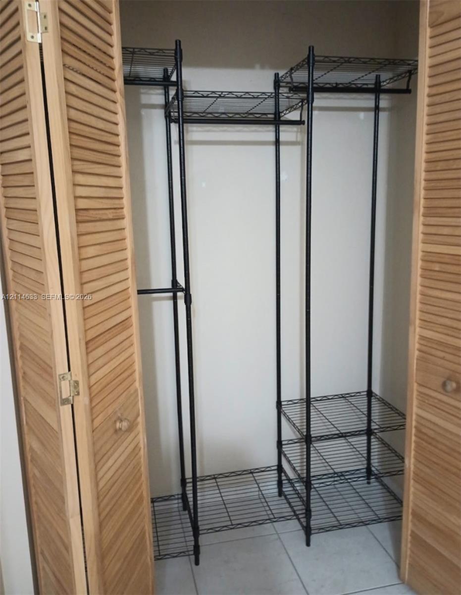 Closet featuring light-tone wood louvered doors, black metal wire shelving, and overhead storage tiers