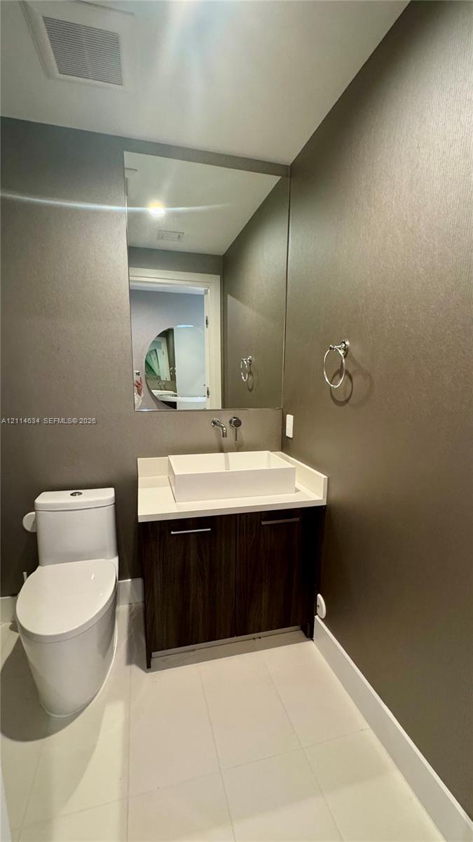 Modern vanity featuring a rectangular vessel sink, white stone countertop, wood-finish cabinetry, and a wall-mounted faucet