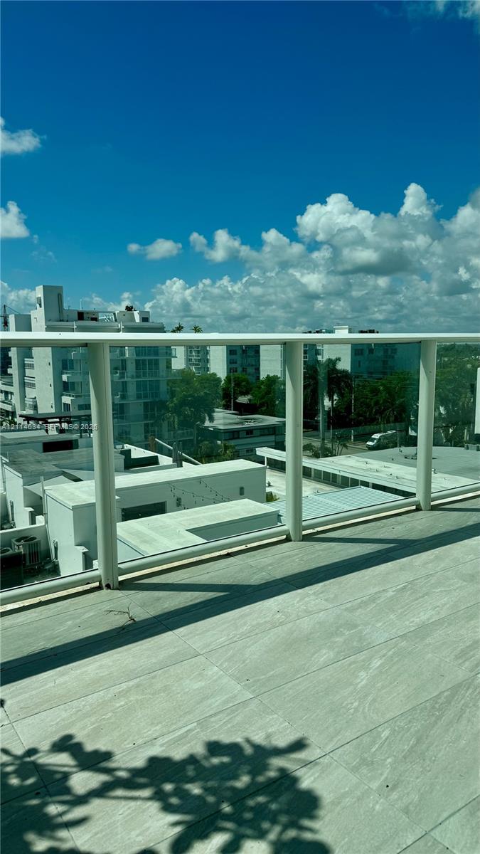 Balcony with large-format light-toned tile flooring and a glass panel railing with white framing Balcony with large-format light-toned tile flooring and a glass panel railing with white framing