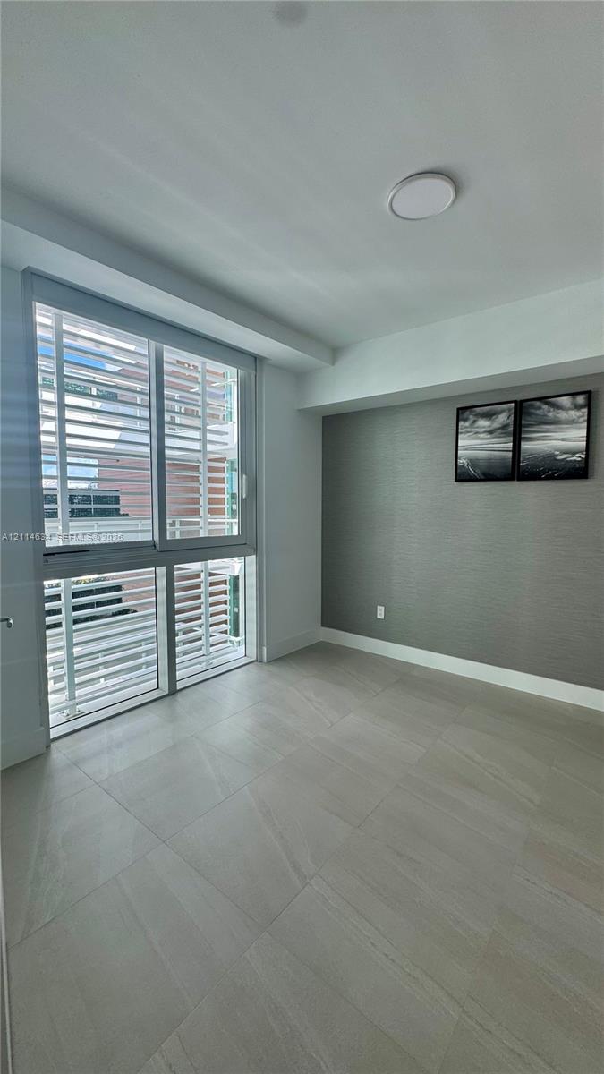 Large-format tile flooring, textured charcoal accent wall, floor-to-ceiling multi-panel window, and recessed ceiling lighting