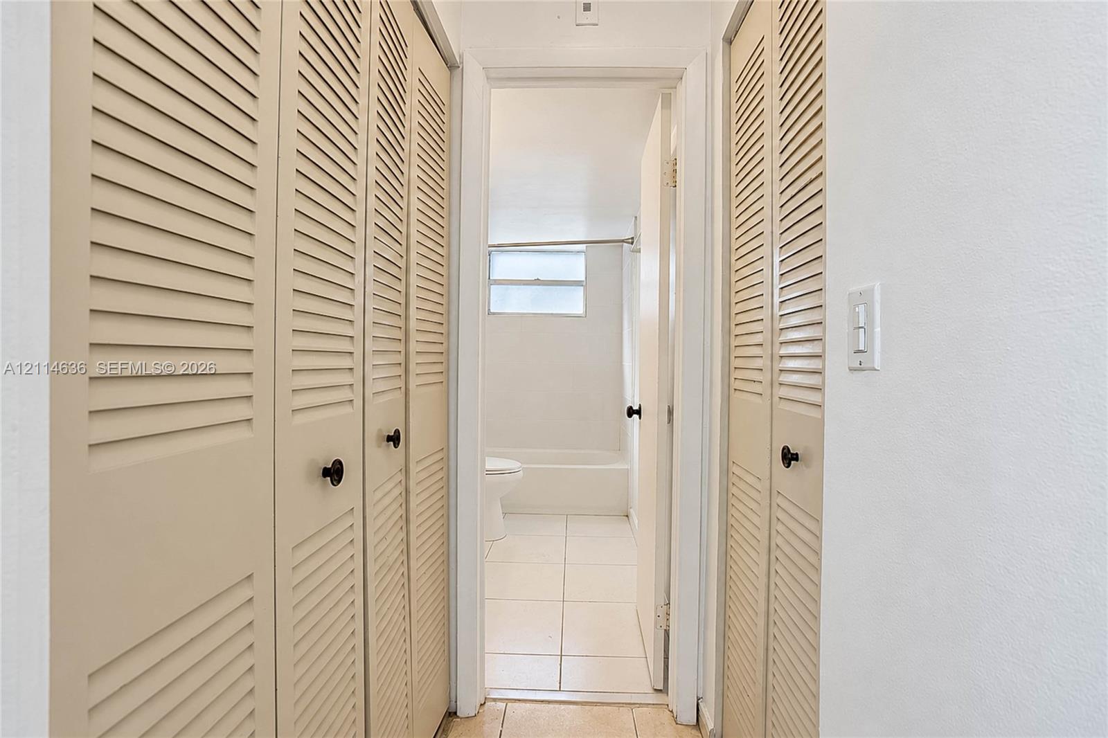 Floor-to-ceiling bi-fold louvered closet doors and tile flooring