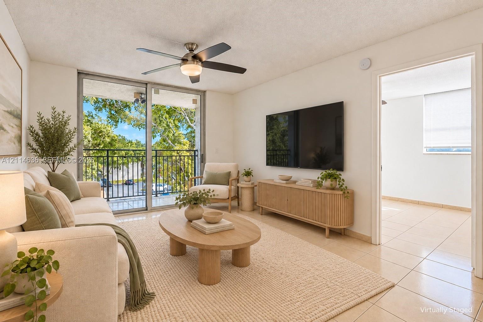 Living area featuring tile flooring, ceiling fan with integrated lighting, and a sliding glass door providing access to a balcony with metal railings