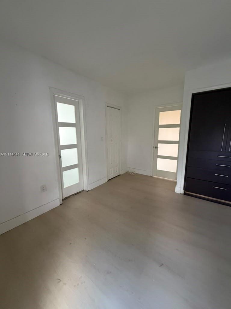 Light-toned wood-finish flooring, dark-toned built-in cabinetry, and dual interior doors featuring four-pane frosted glass inserts