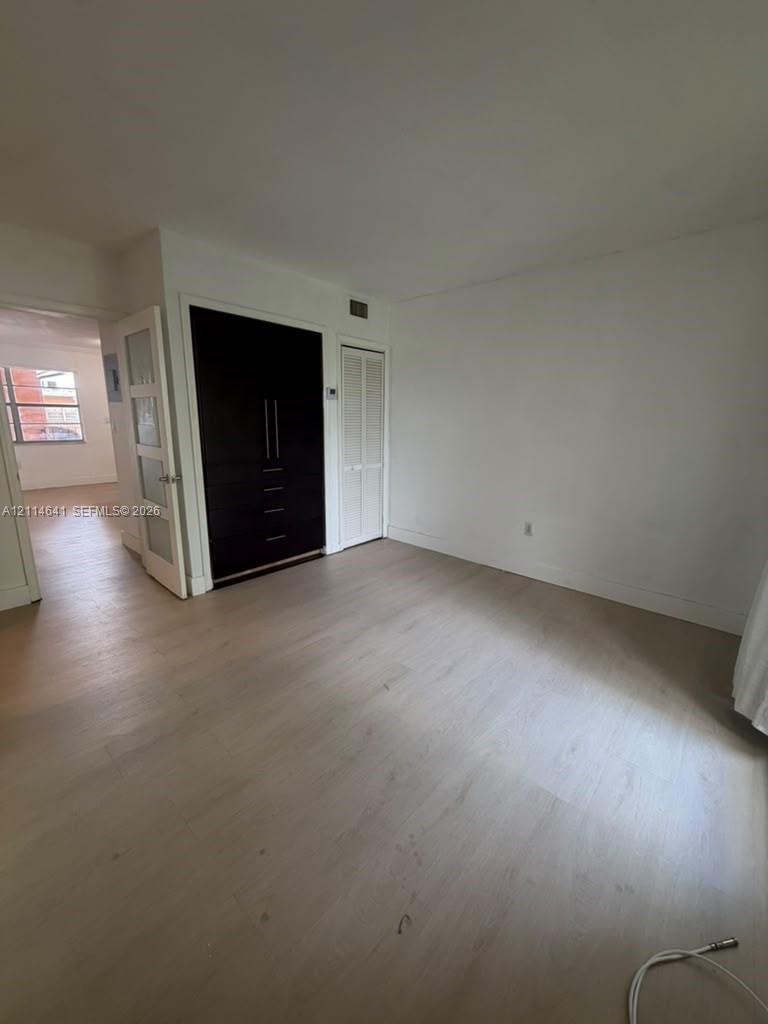 Room featuring wood-finish flooring, built-in floor-to-ceiling cabinetry with integrated drawers, and a glass-paneled interior door