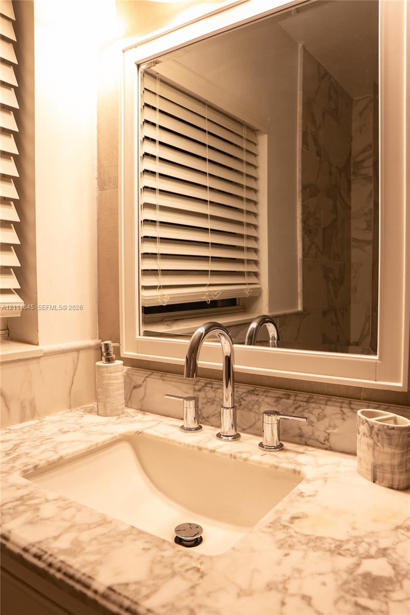 Stone countertop with an integrated undermount sink, polished chrome widespread faucet, and framed wall-mounted mirror