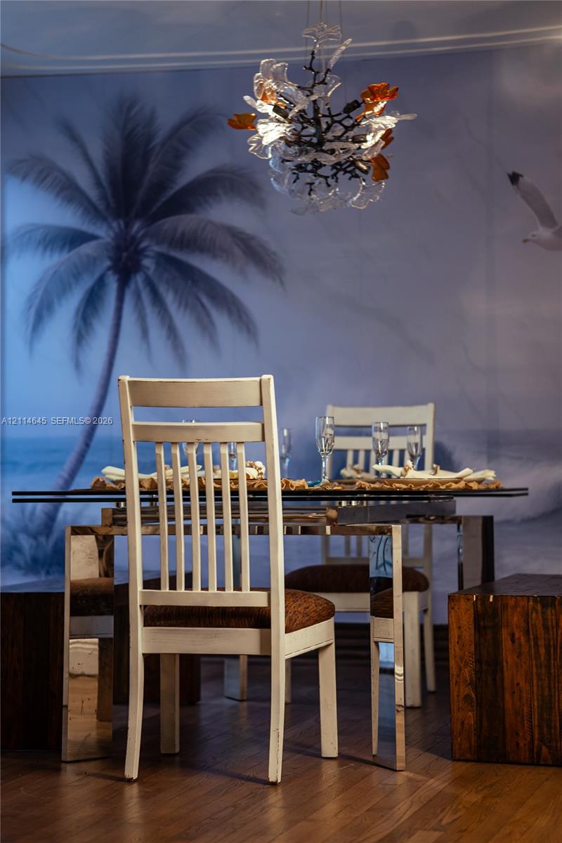 Artistic chandelier featuring delicate glass accents and branch-inspired frame, complemented by wood-finish flooring and panoramic mural wall covering