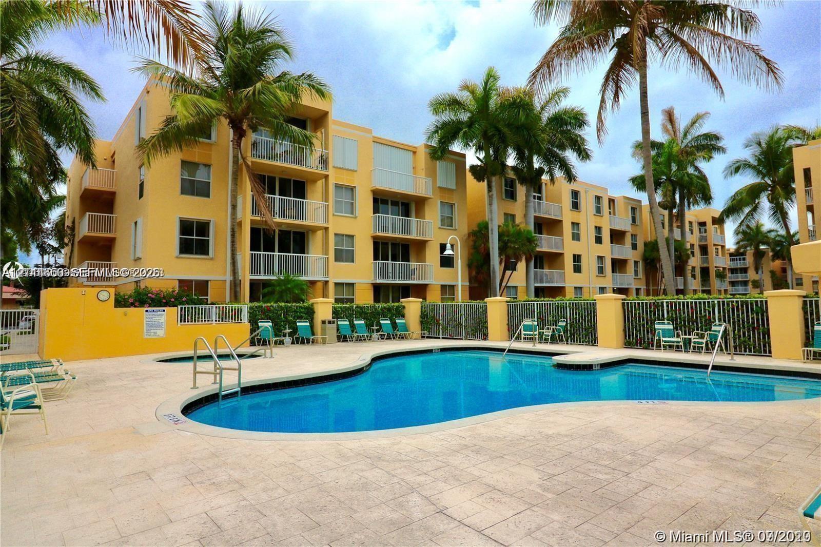 Swimming pool with integrated spa and stone-paved deck, surrounded by mature palm trees and multi-story residential buildings featuring private balconies
