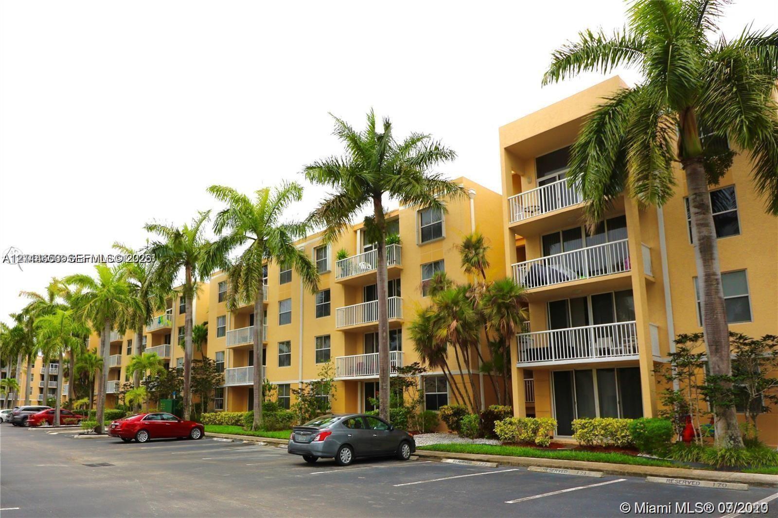 Multi-story residential building exterior featuring stucco facade, private balconies with white railings, and mature palm tree landscaping