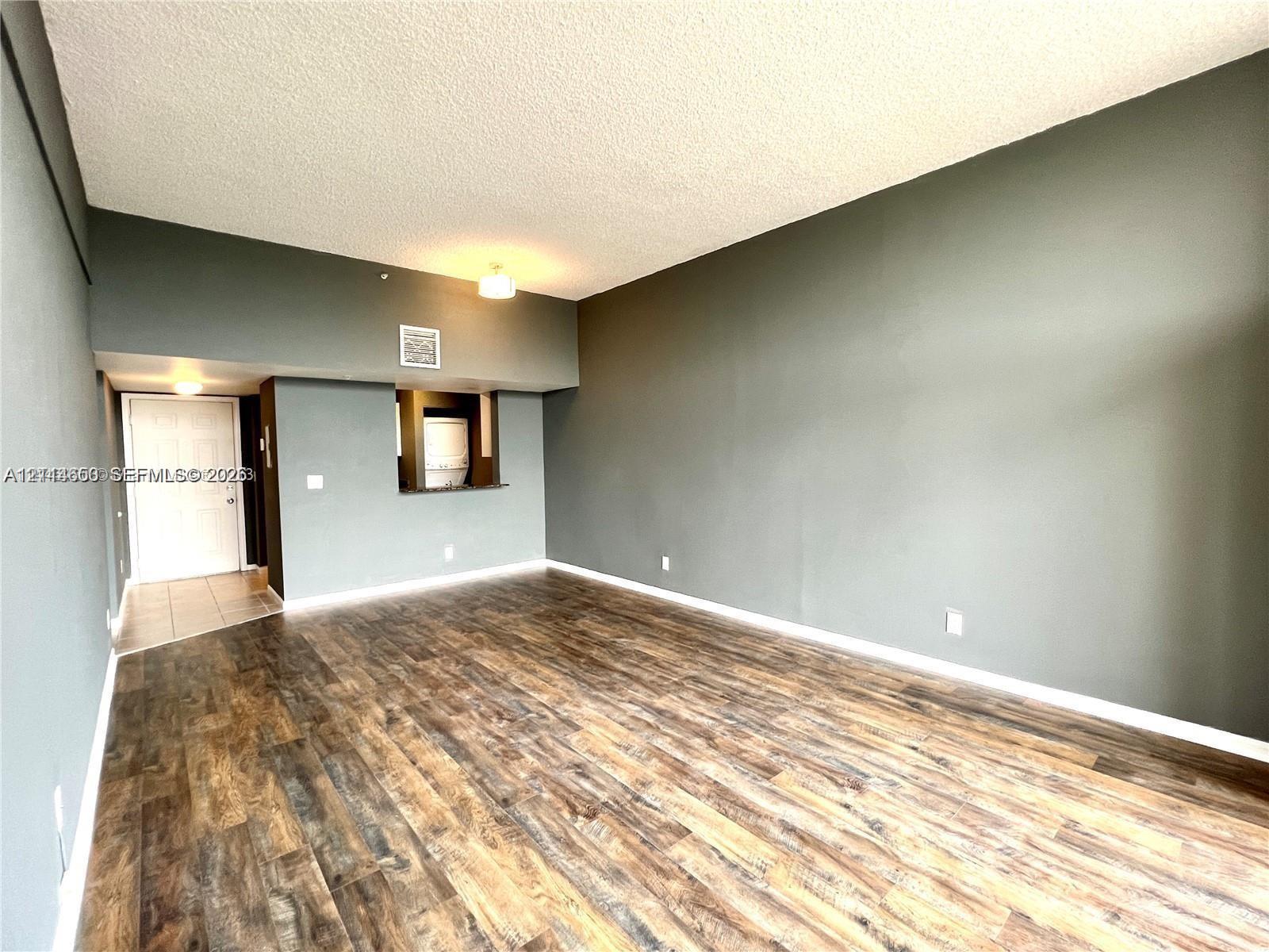 Interior space featuring wood-finish flooring, vaulted ceilings, and a pass-through opening to the kitchen