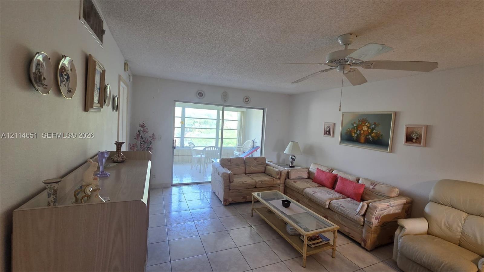 Living area featuring tile flooring, ceiling fan, and sliding glass doors
