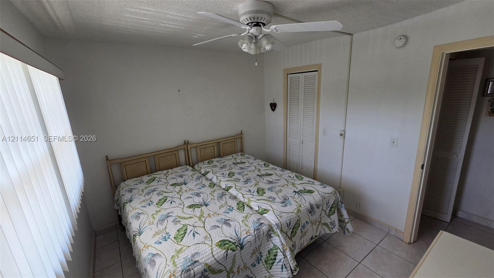Room featuring tile flooring, a ceiling fan with integrated lighting, and vertical window blinds
