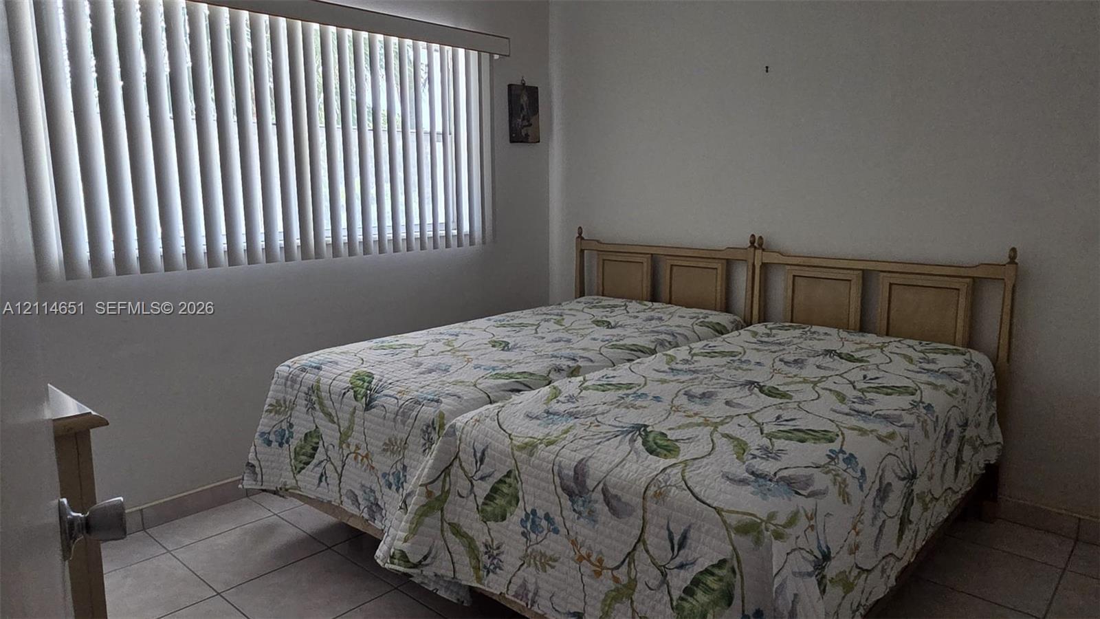 Interior room featuring neutral wall finishes, tile flooring, and vertical window blinds