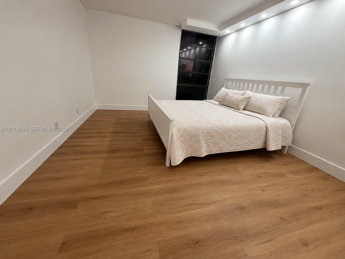 Neutral interior space featuring wood-finish flooring, floor-to-ceiling window, and recessed ceiling lighting