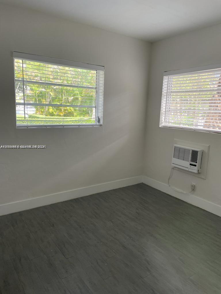 Interior space featuring wood-finish flooring, two horizontal slider windows, and a wall-mounted air conditioning unit