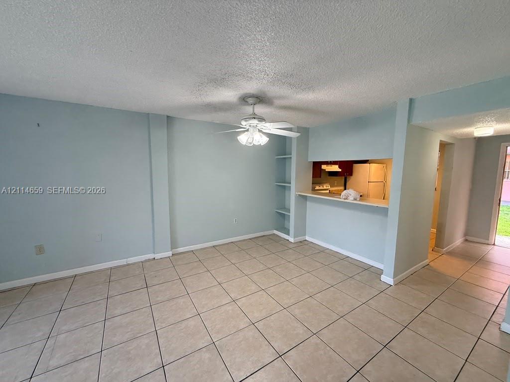 Ceramic tile flooring, ceiling-mounted fan with integrated lighting, and built-in wall shelving