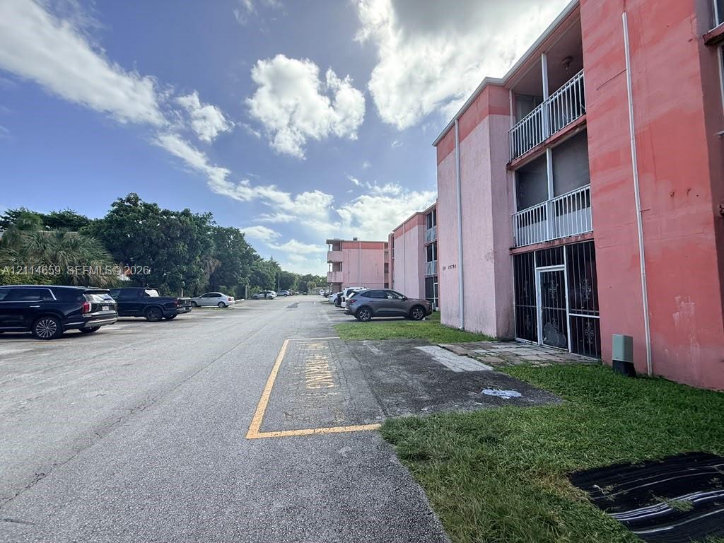 Multi-story exterior featuring paved surface parking and private balconies with metal railings