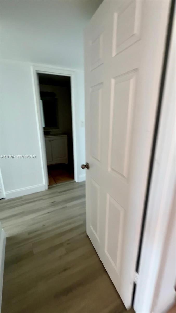 Six-panel interior door with a satin-nickel lever handle, wood-finish flooring, and white interior trim Six-panel interior door with a satin-nickel lever handle, wood-finish flooring, and white interior trim