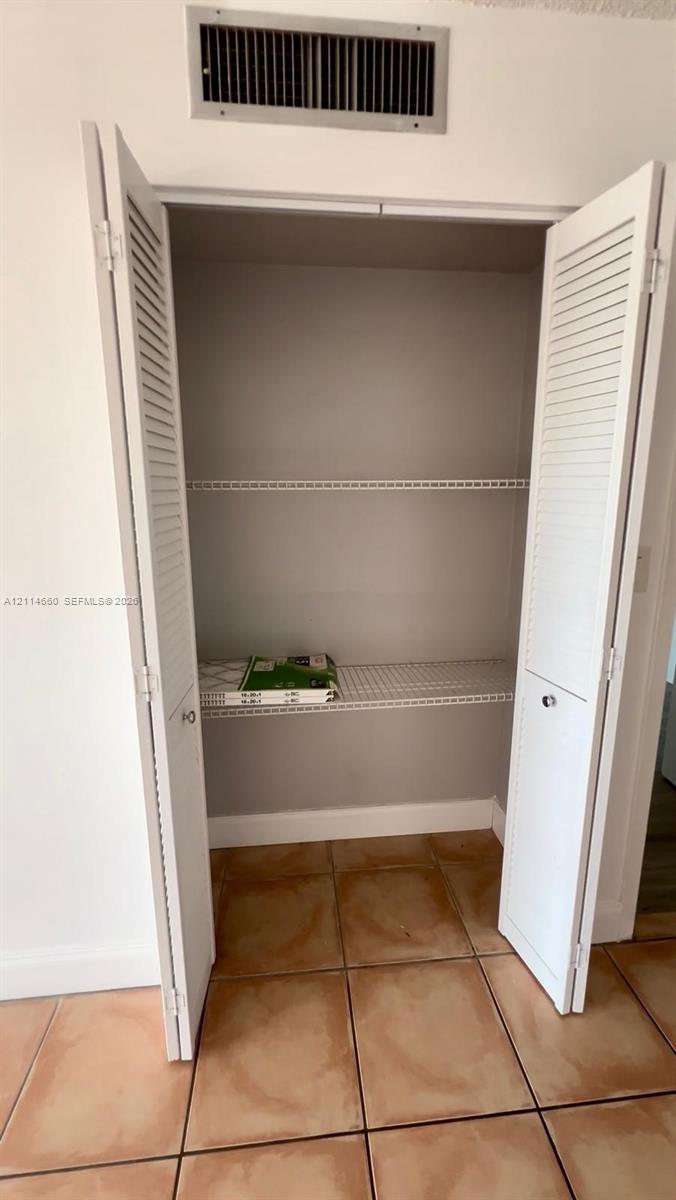 Closet featuring white louvered bifold doors and wire shelving on tile flooring Closet featuring white louvered bifold doors and wire shelving on tile flooring
