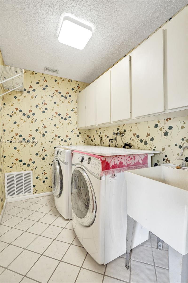 Laundry area featuring white built-in cabinetry, a utility sink, and diamond-pattern tile flooring