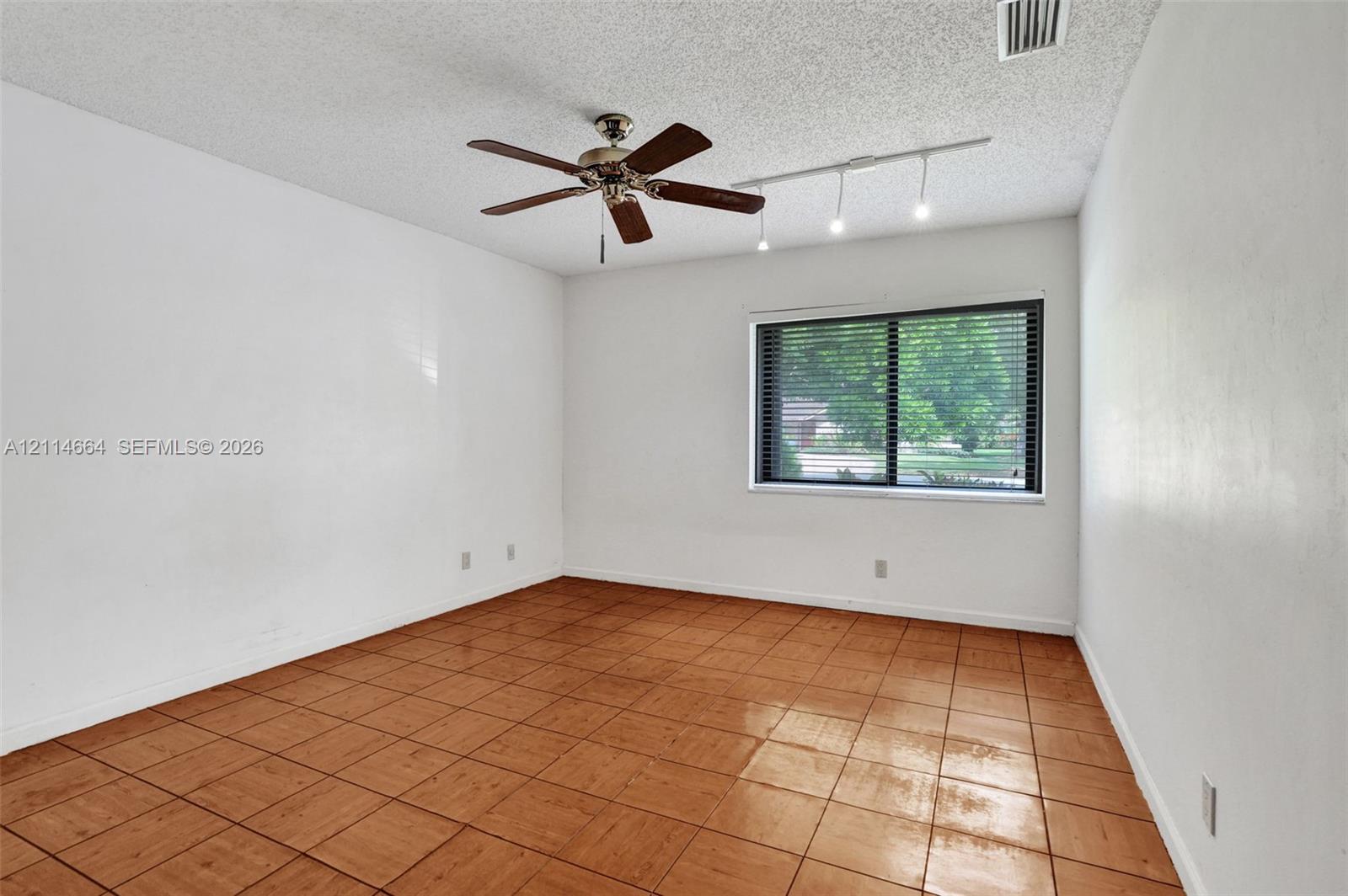 Room featuring large-format ceramic tile flooring, a multi-blade ceiling fan, and adjustable track lighting
