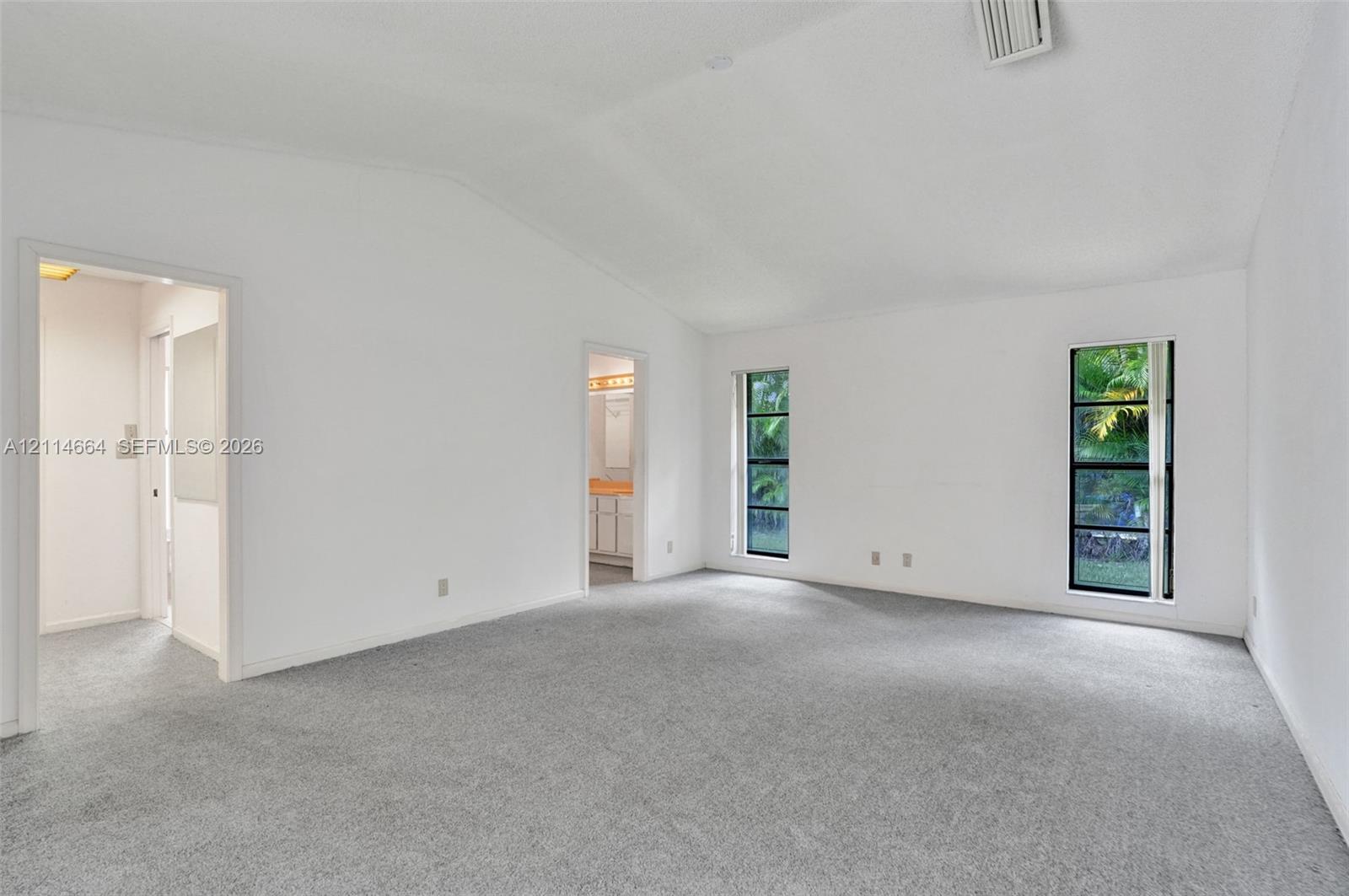 Vaulted ceilings, neutral carpeting, and dual vertical windows with exterior landscape exposure