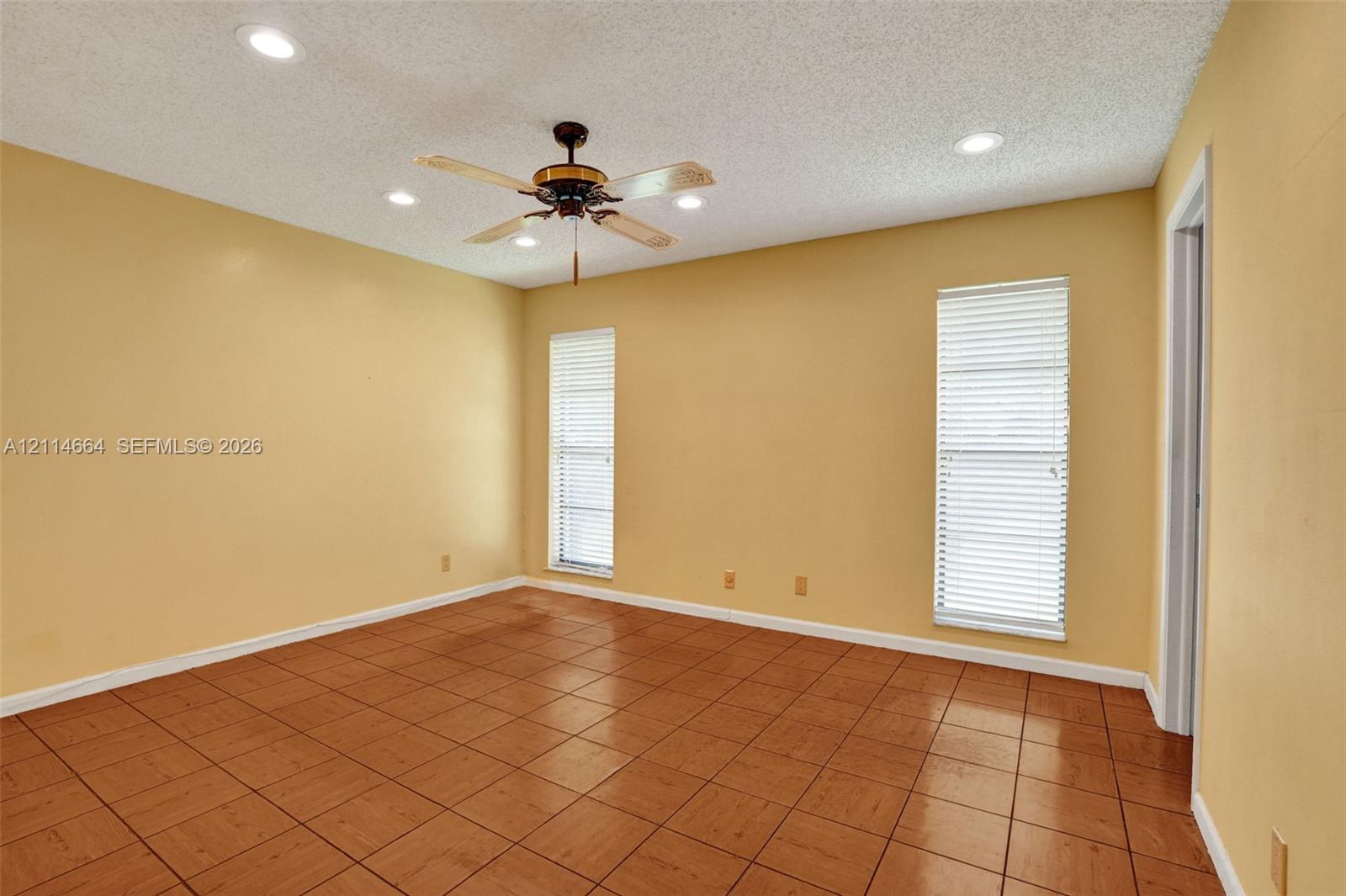 Ceramic tile flooring, recessed lighting, and a ceiling fan with integrated lighting, finished with two windows featuring horizontal blinds