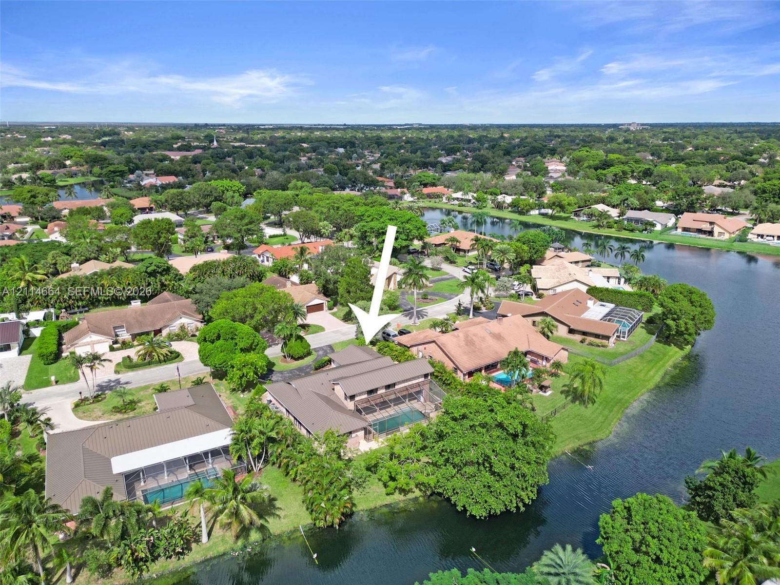 Waterfront residence featuring a screened-in swimming pool, a multi-level roof structure, and extensive landscaping