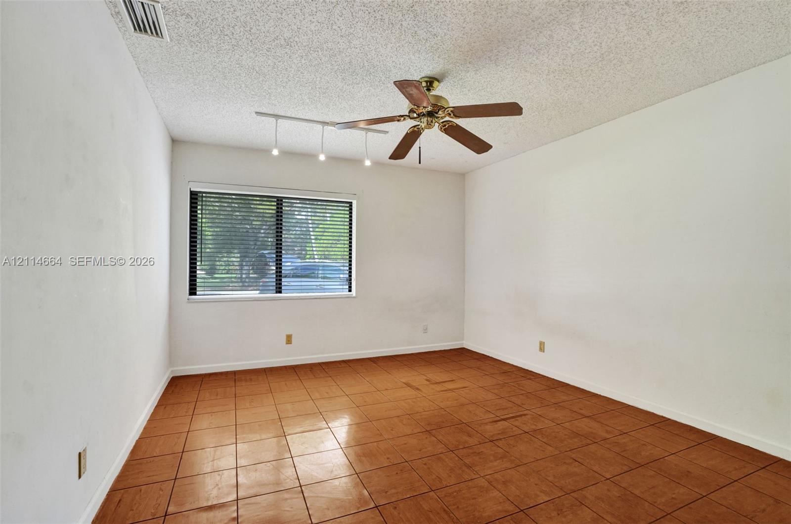 Room featuring tile flooring, ceiling fan with integrated light fixture, and track lighting
