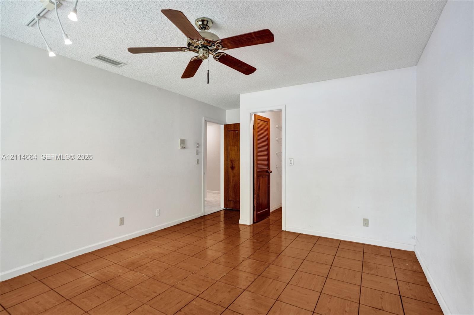 Room featuring ceramic tile flooring, a central ceiling fan with integrated lighting, and a multi-directional track lighting fixture
