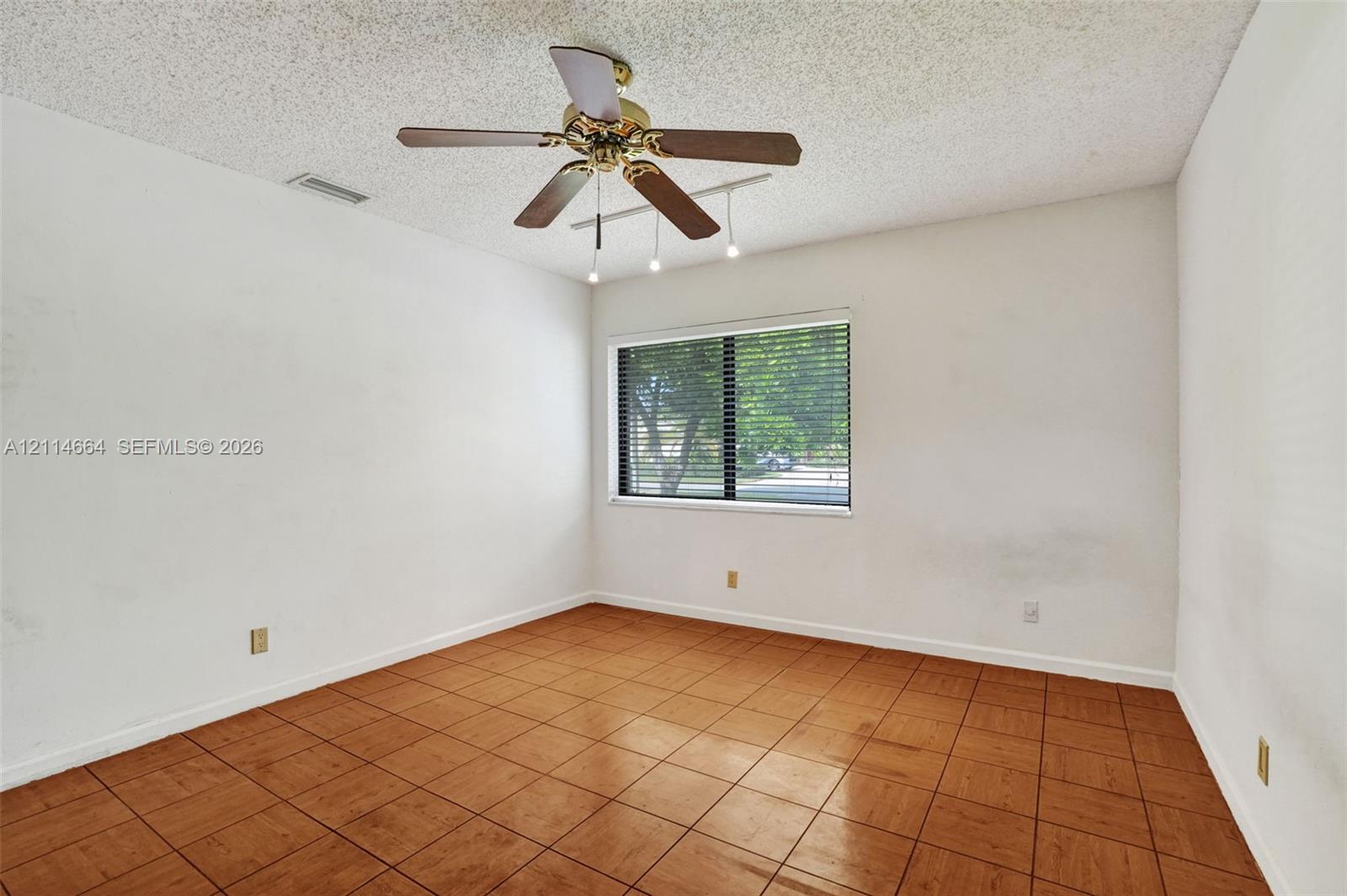Interior room featuring ceramic tile flooring, a multi-blade ceiling fan with integrated lighting, and a window with horizontal blinds