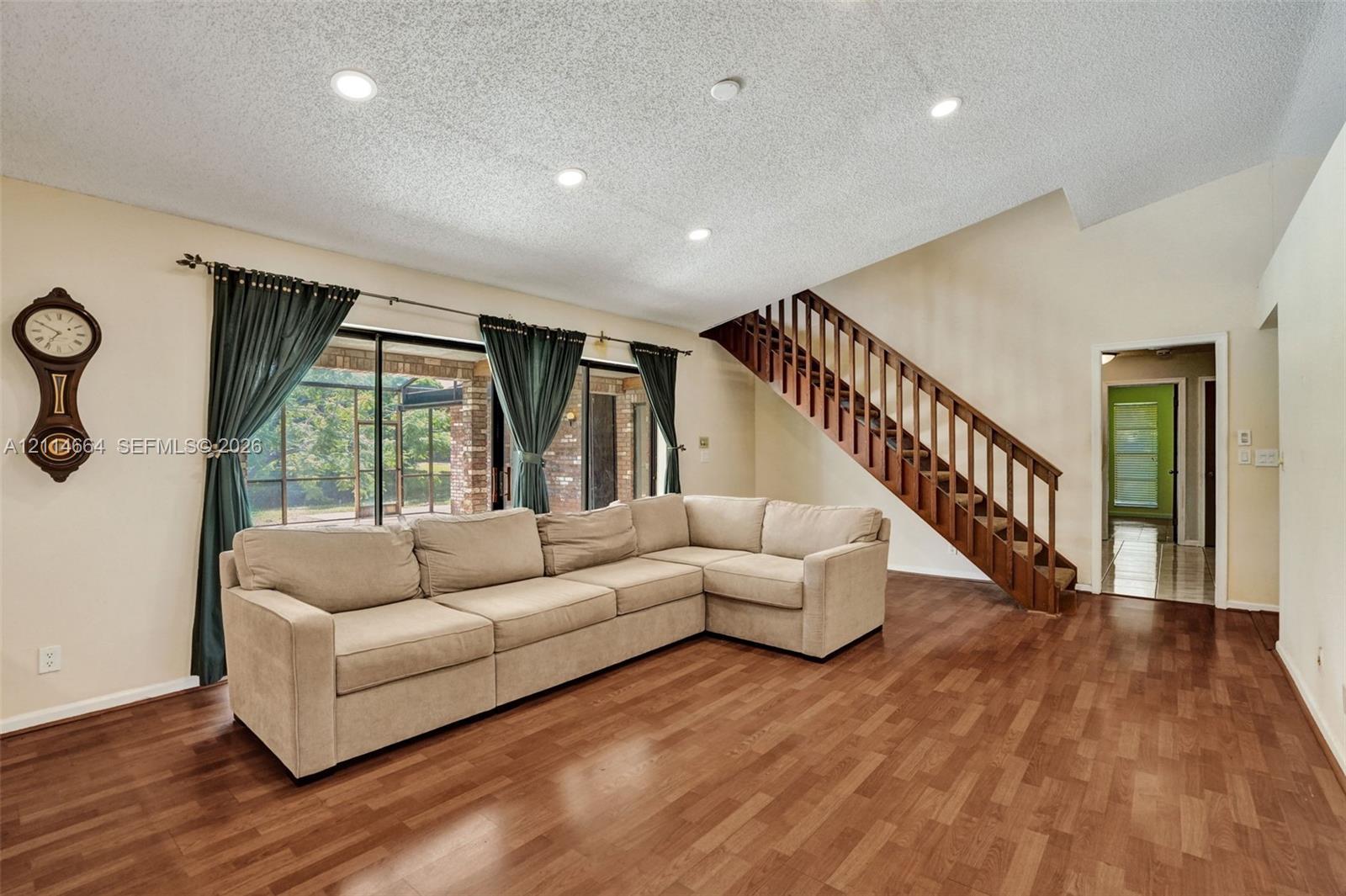 Vaulted ceilings with recessed lighting, wood-finish flooring, and a wooden staircase featuring open-riser styling and railings