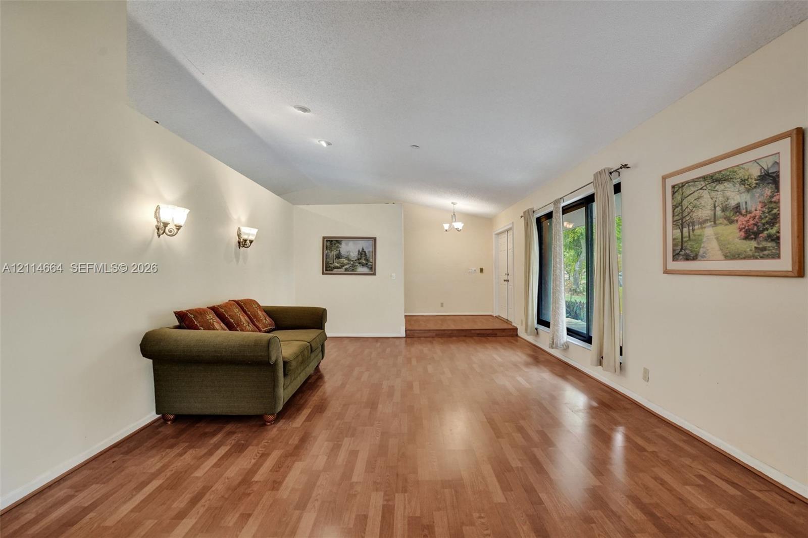 Wood-finish flooring, vaulted ceilings, wall-mounted light fixtures, and expansive windows