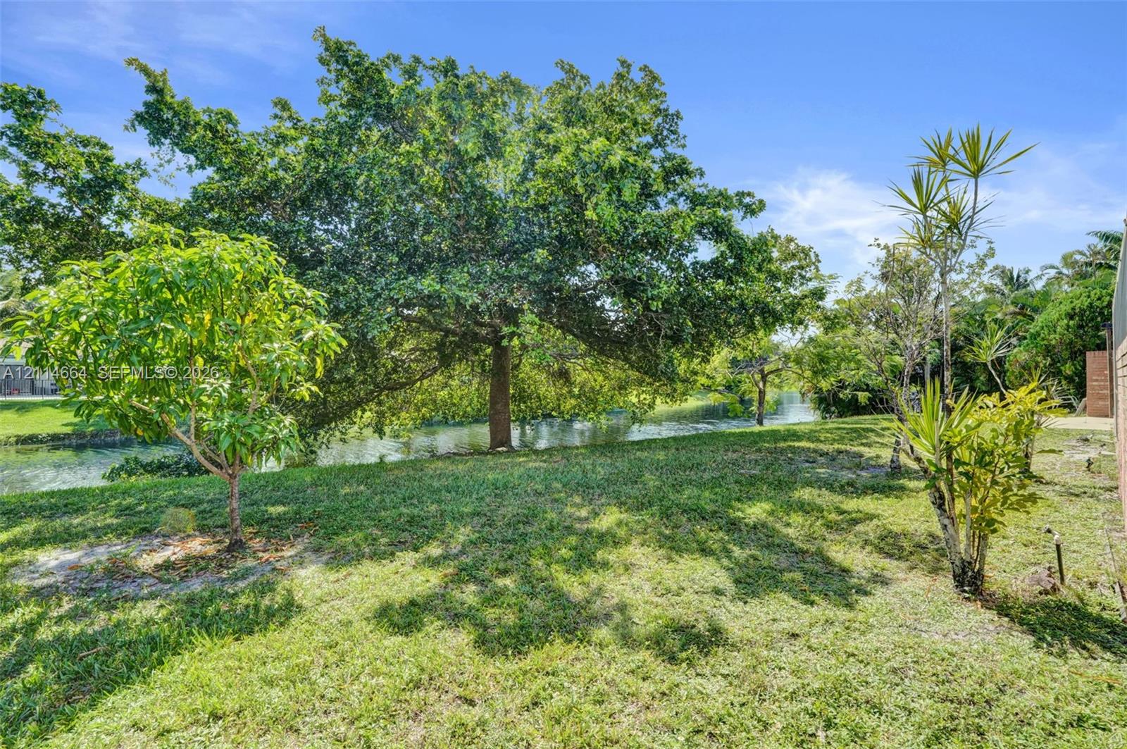 Waterfront lot featuring mature canopy trees, established landscaping, and open green space