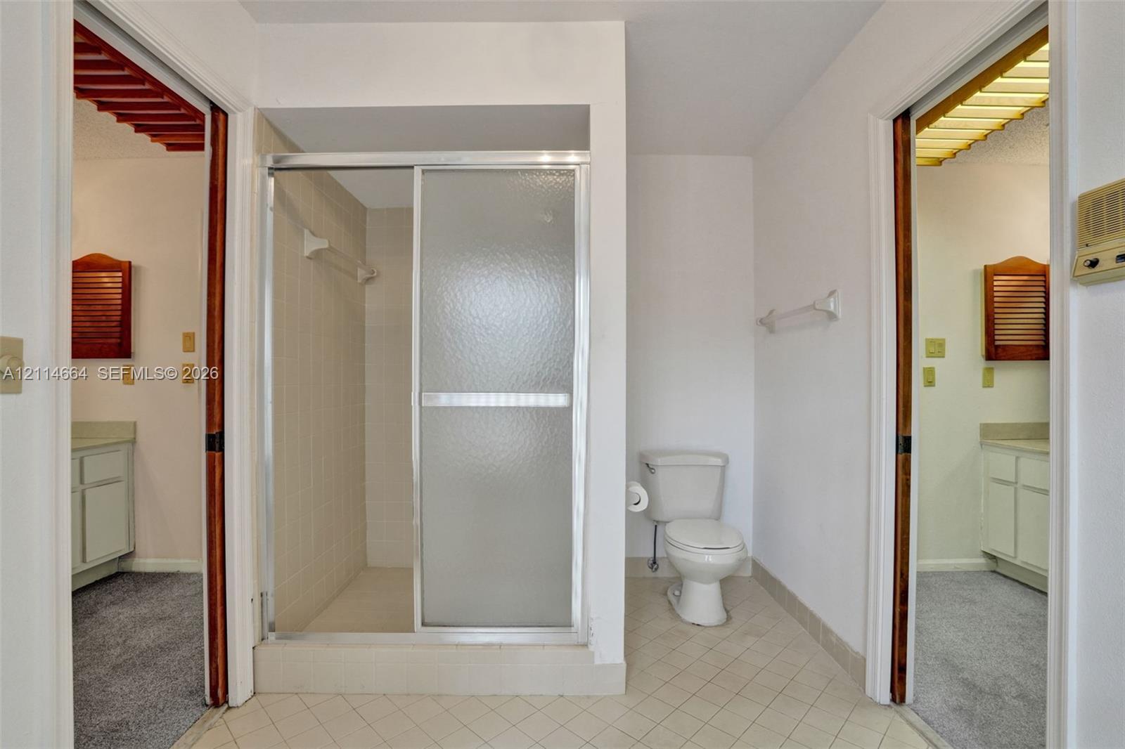 Bathroom featuring a walk-in shower with a glass sliding door, ceramic tile flooring, and wall-mounted towel bars