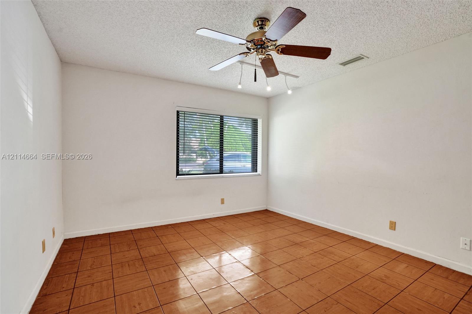 Room featuring ceramic tile flooring, a multi-blade ceiling fan with integrated lighting, and a single-pane window with horizontal blinds