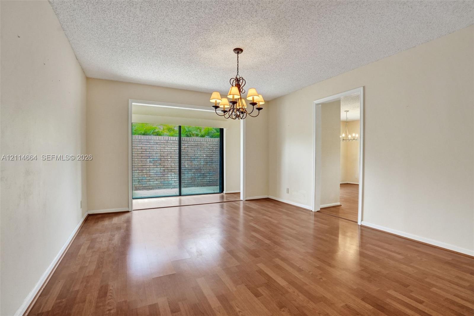 Interior space featuring wood-finish flooring, a multi-arm chandelier, and sliding glass doors with brick exterior wall exposure