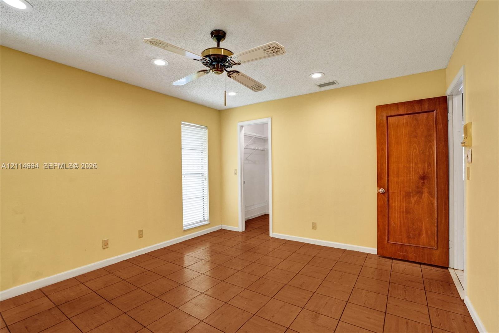 Interior space featuring tile flooring, ceiling fan with light fixture, recessed lighting, and a solid wood door