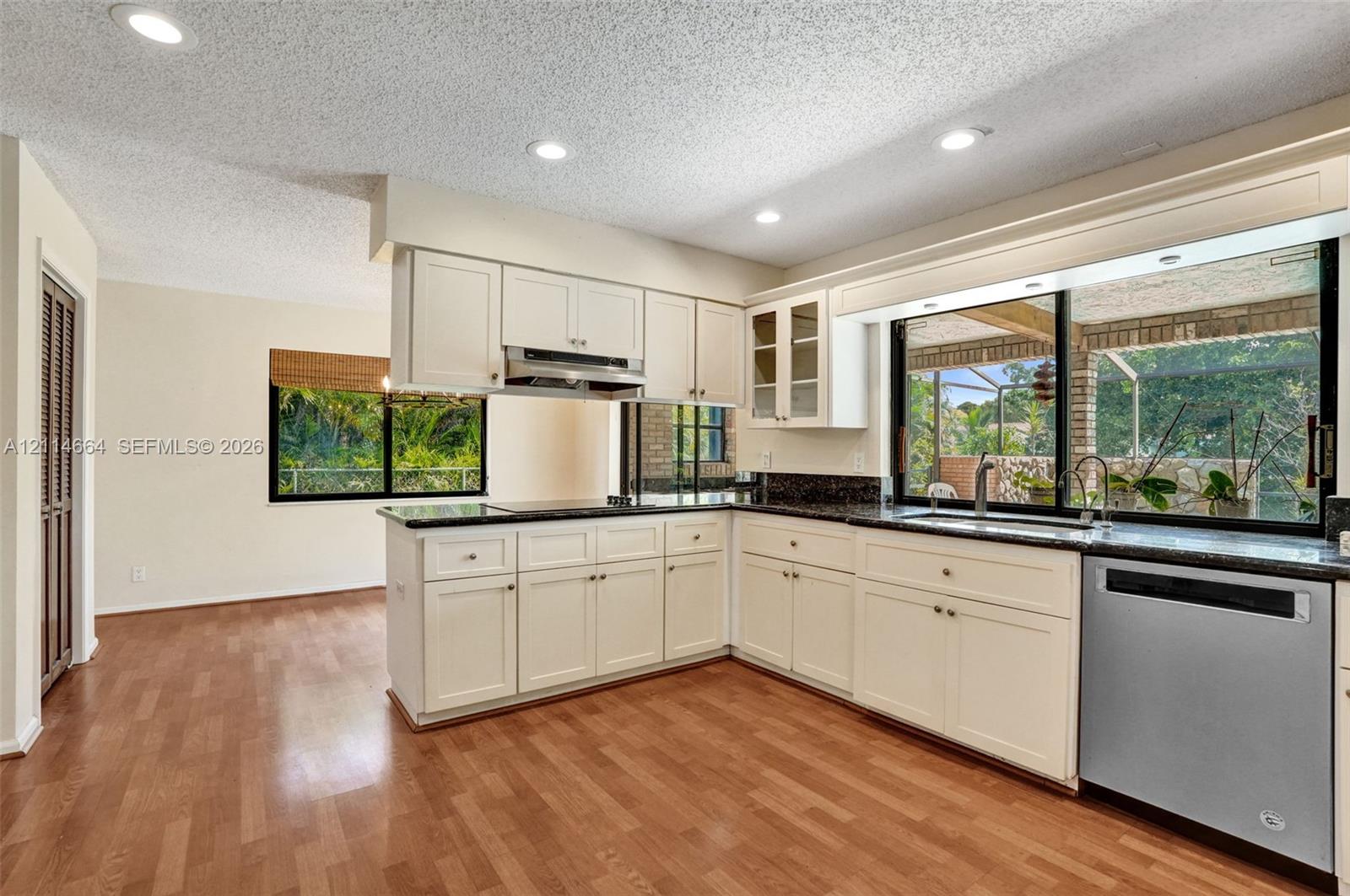 Kitchen featuring cream-colored cabinetry, stone countertops, stainless steel dishwasher, recessed lighting, and wood-finish flooring