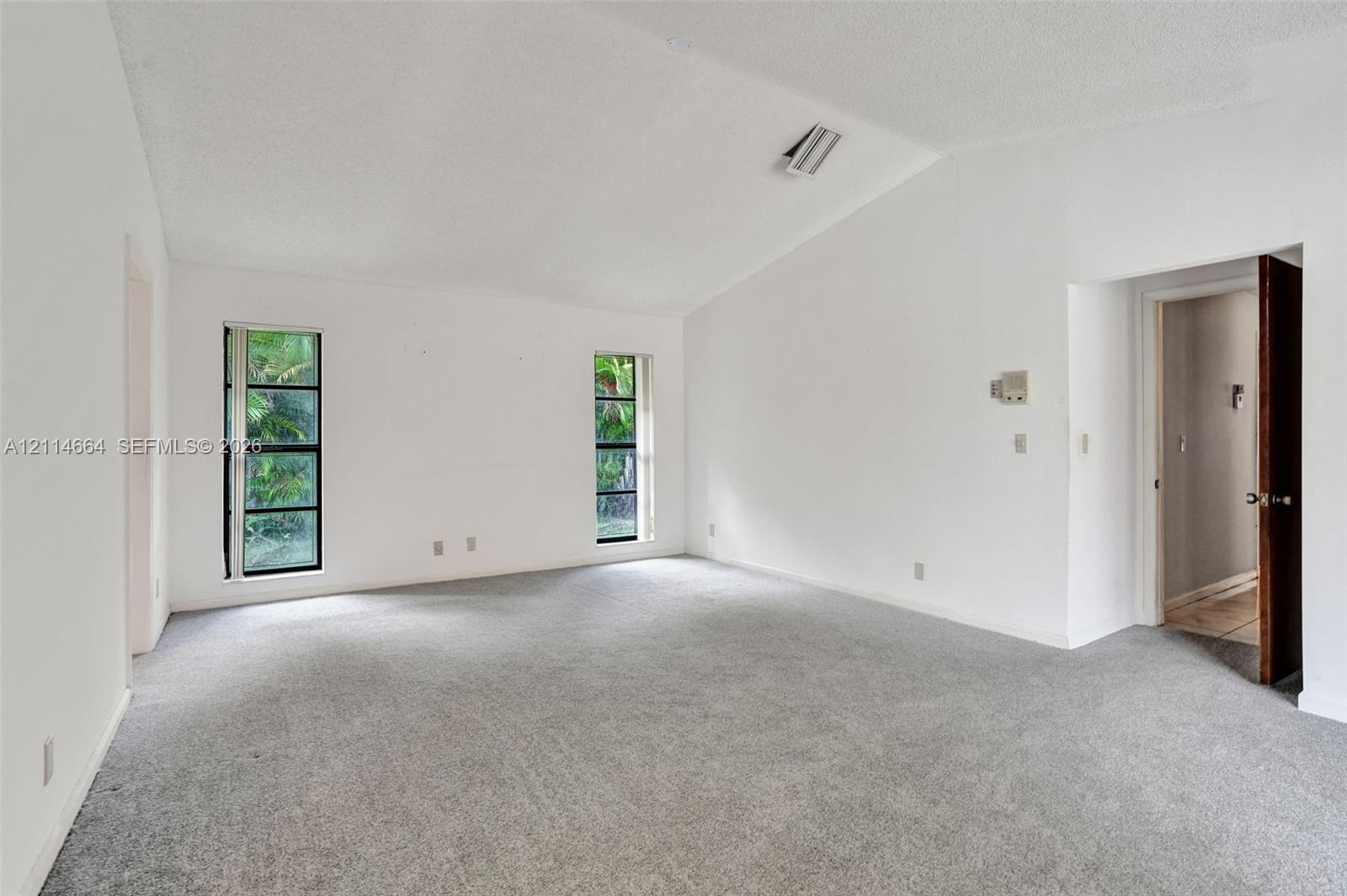 Vaulted ceiling, neutral wall-to-wall carpeting, and dual rectangular windows featuring black frames