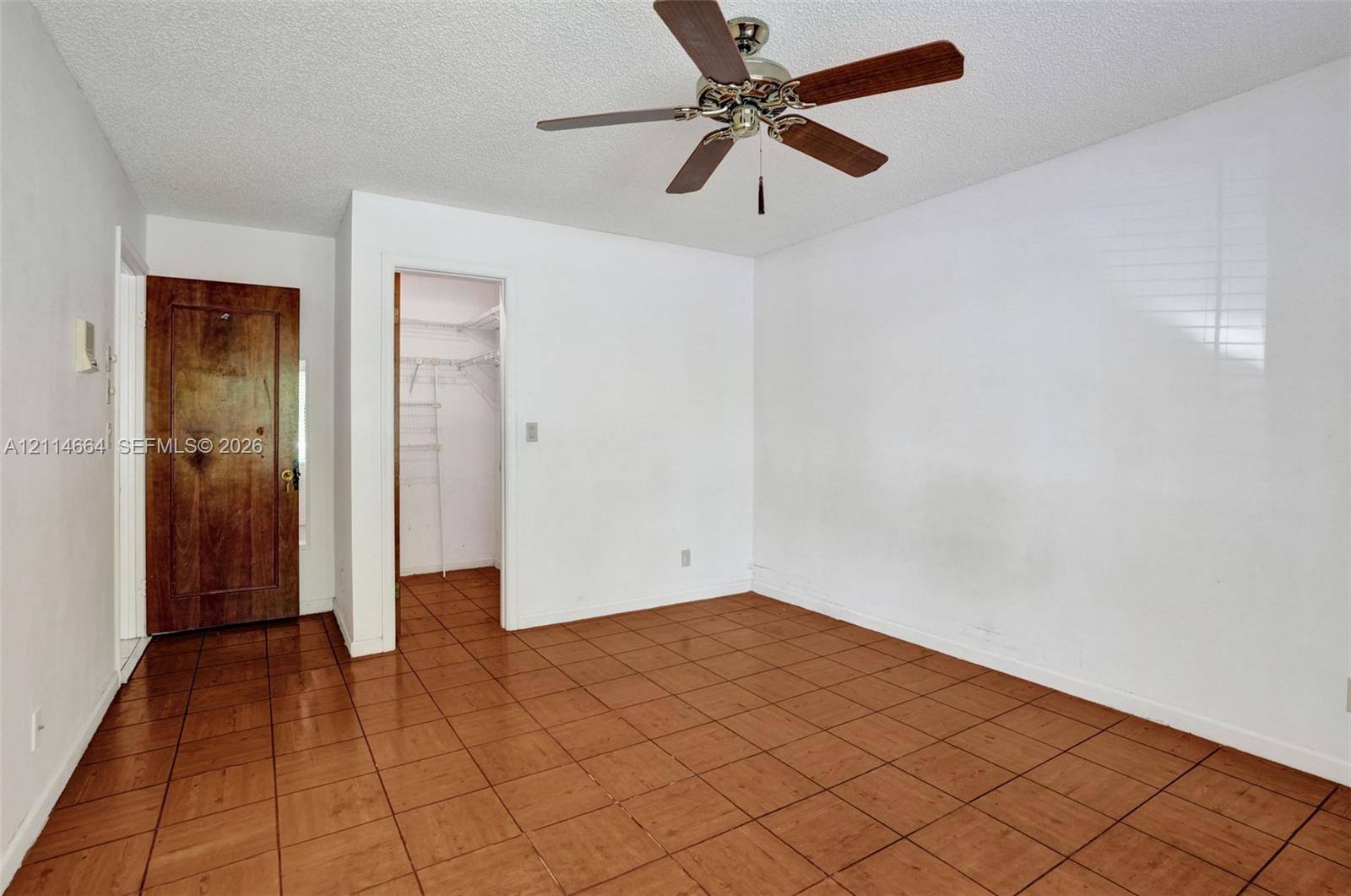 Interior room featuring ceramic tile flooring, a ceiling fan with integrated lighting, and a solid wood door