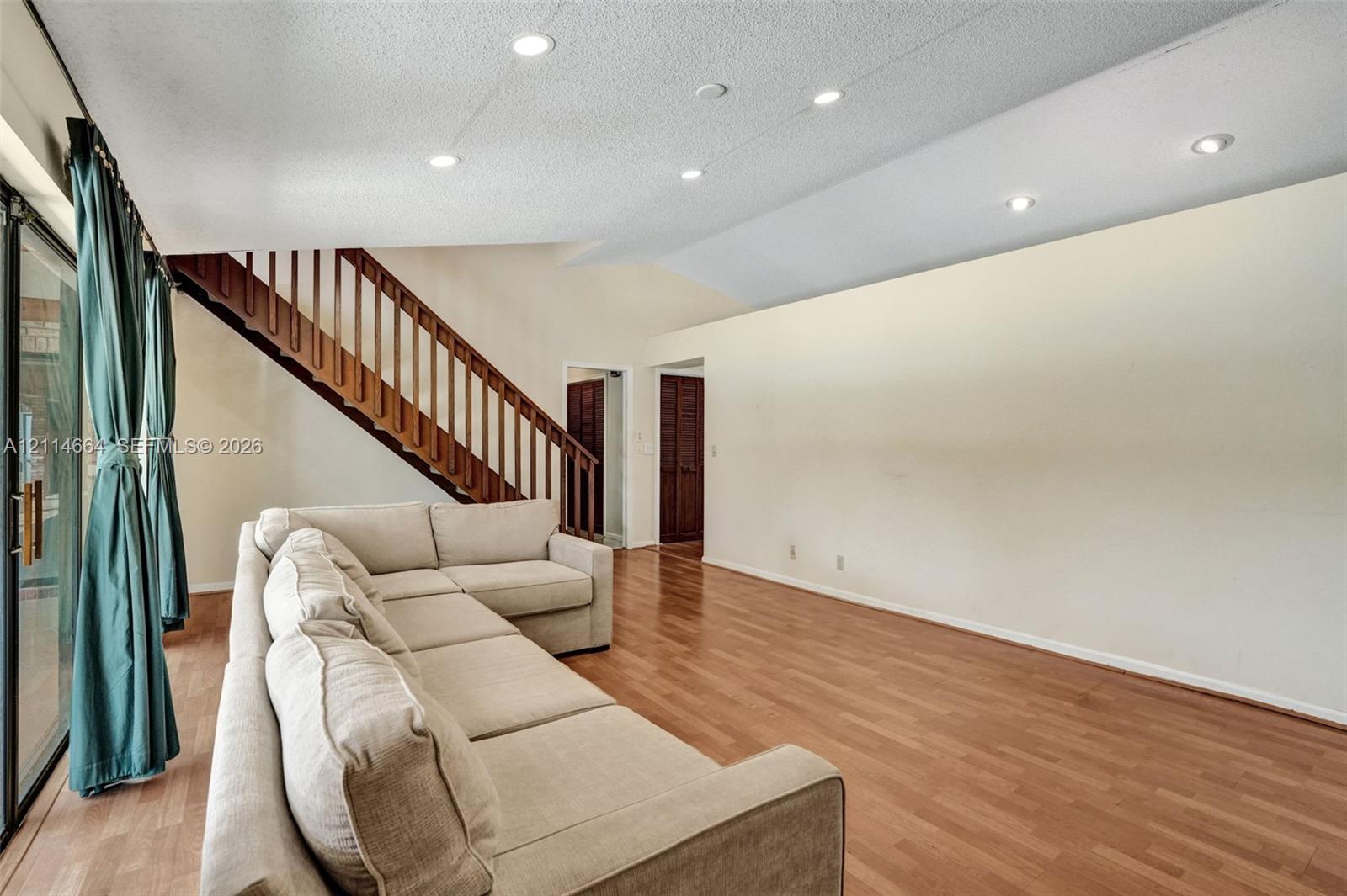 Vaulted ceilings, wood-finish flooring, recessed lighting, and a wooden staircase with vertical railing