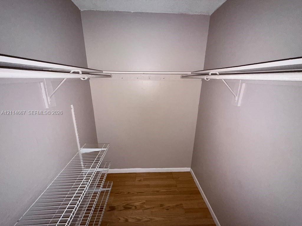 Storage area featuring wood-finish flooring, white wire shelving, and dual-level hanging rods