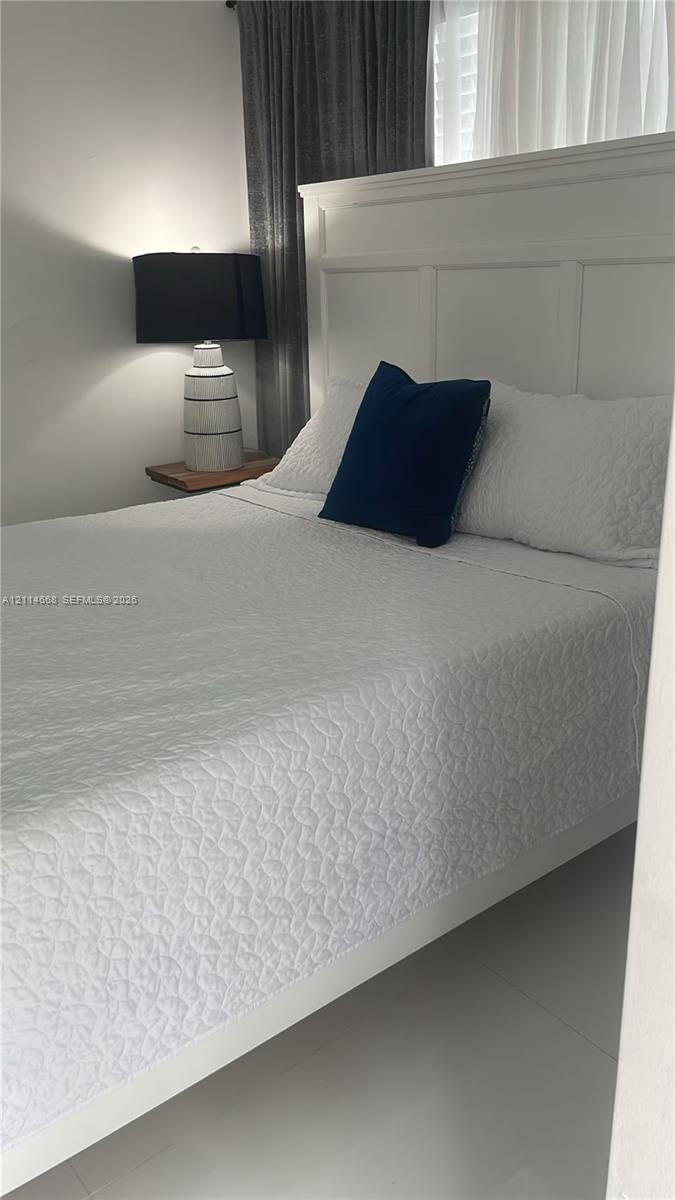 Wall-mounted floating wooden bedside shelf, white panel-style headboard, and smooth tile flooring