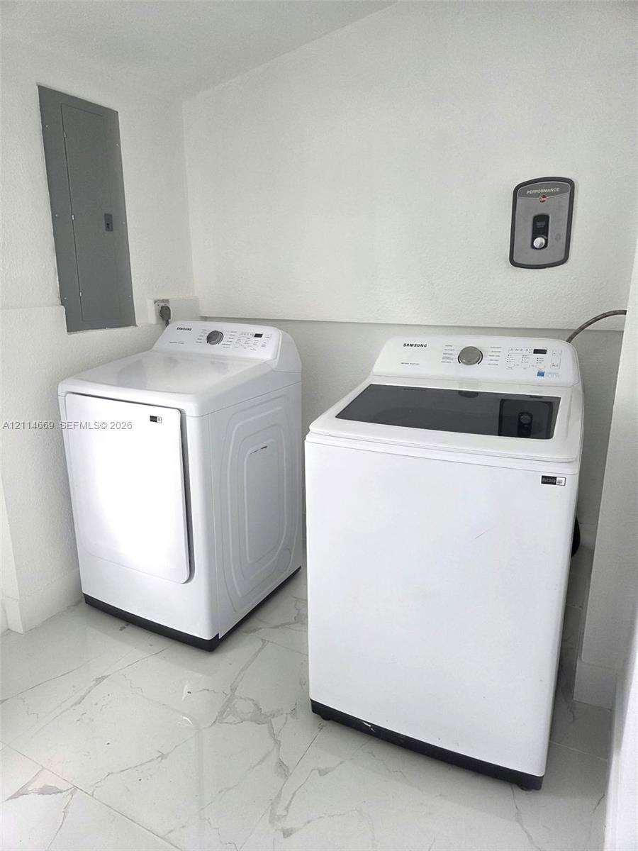 Laundry area featuring high-gloss tile flooring, white walls, and built-in electrical service panel Laundry area featuring high-gloss tile flooring, white walls, and built-in electrical service panel
