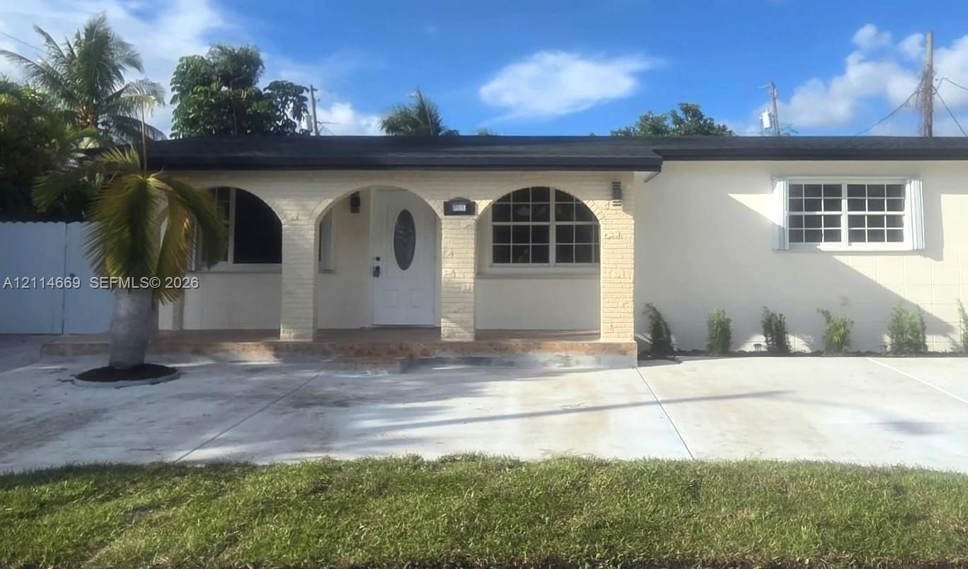 Single-story exterior featuring a brick facade with arched entryway columns, a white oval-lite front door, grid-pattern windows, and a concrete driveway Single-story exterior featuring a brick facade with arched entryway columns, a white oval-lite front door, grid-pattern windows, and a concrete driveway