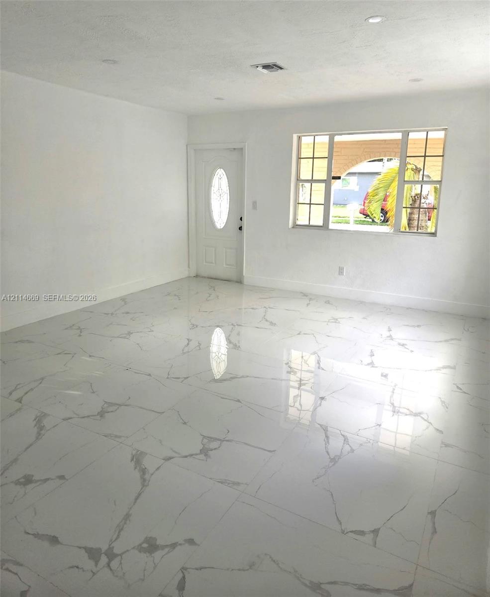 Large-format polished tile flooring, recessed ceiling lighting, and a multi-pane window featuring grid detailing Large-format polished tile flooring, recessed ceiling lighting, and a multi-pane window featuring grid detailing