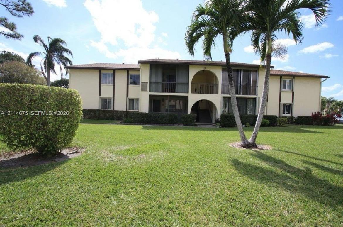 Two-story multi-unit exterior featuring arched architectural detailing, screened-in balcony enclosures, low-slope rooflines, and manicured landscaping Two-story multi-unit exterior featuring arched architectural detailing, screened-in balcony enclosures, low-slope rooflines, and manicured landscaping