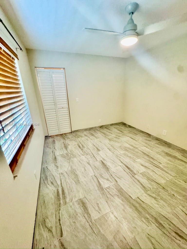 Room featuring wood-finish tile flooring, a ceiling fan with integrated lighting, and louvered bifold closet doors
